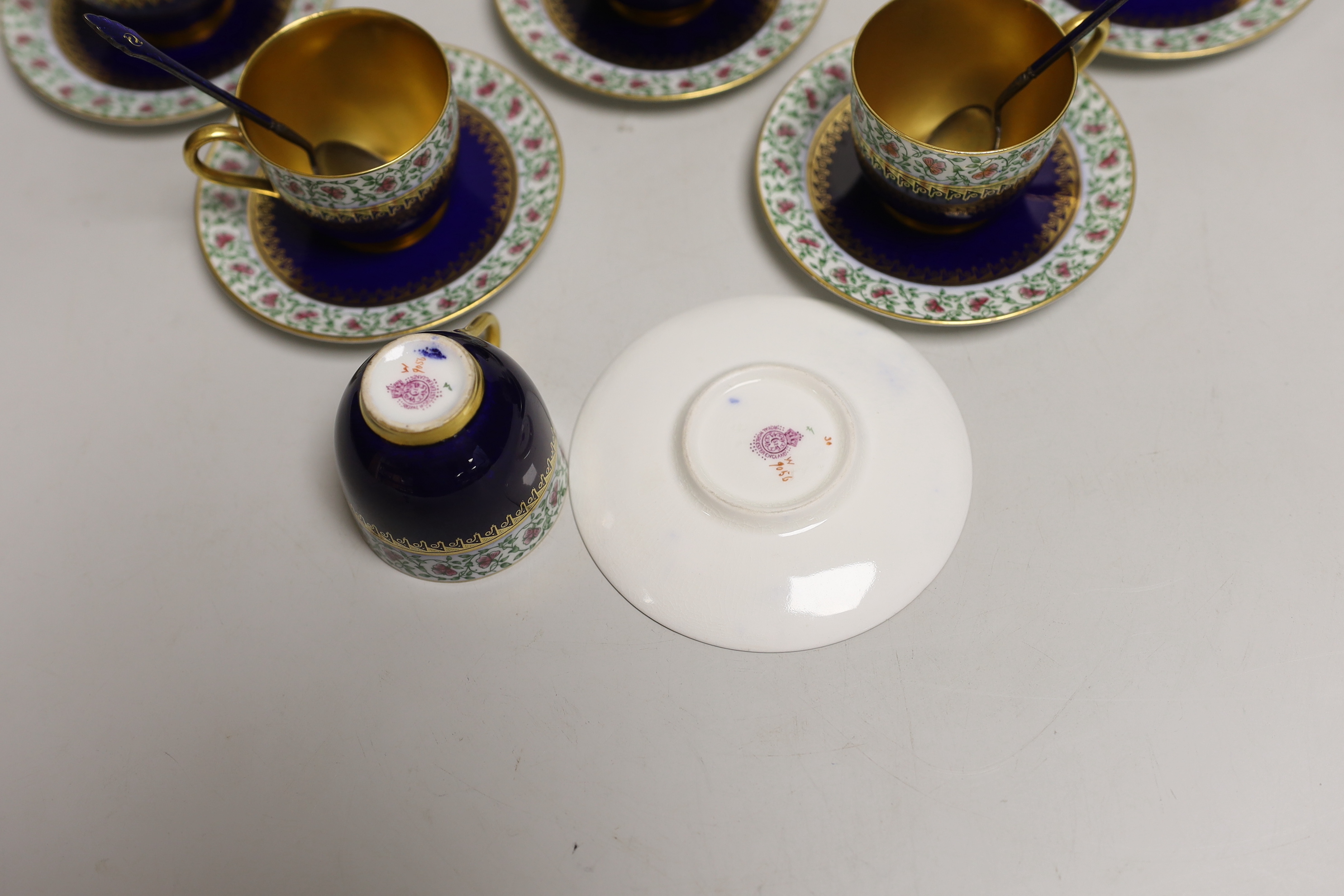 A set of six Royal Worcester porcelain coffee cups and saucers, together with a set of six silver and blue enamelled spoons